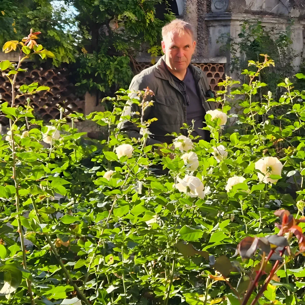 Pascal Steenhuis, Founder of Agaporia, photographed mid-distance among flowering roses in the working garden of the 173-acre estate. Purpose-Driven at the regenerative five-star sanctuary in Tuscany.